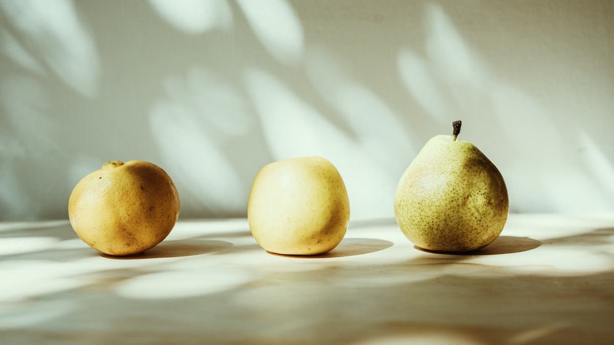 Artistic arrangement of fresh fruits with shadow play on a flat surface.